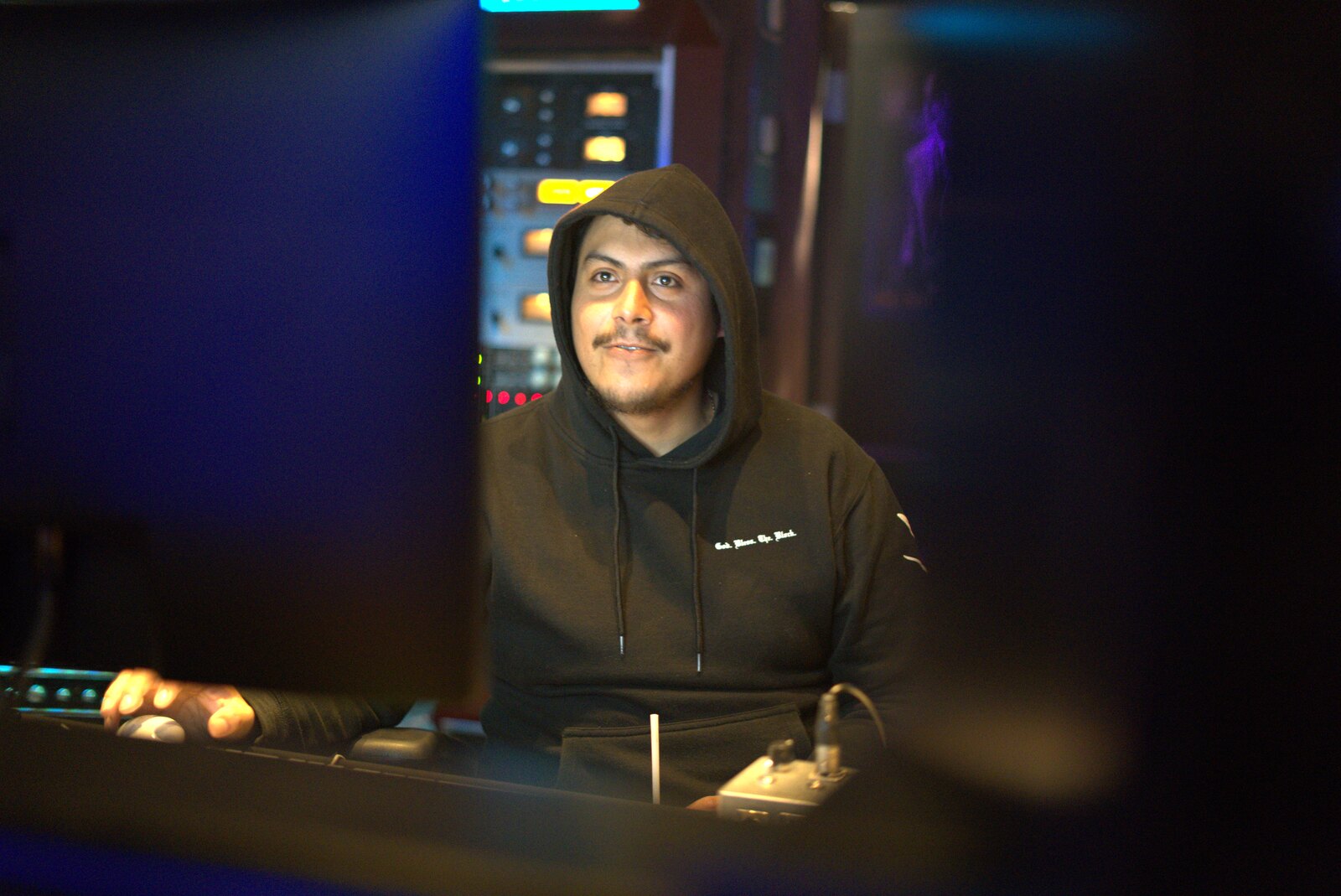 Jonathan De La Torre seated in his studio between monitor screens